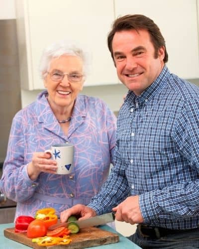 A white senior woman and a whitemiddle-aged man chopping vegetables